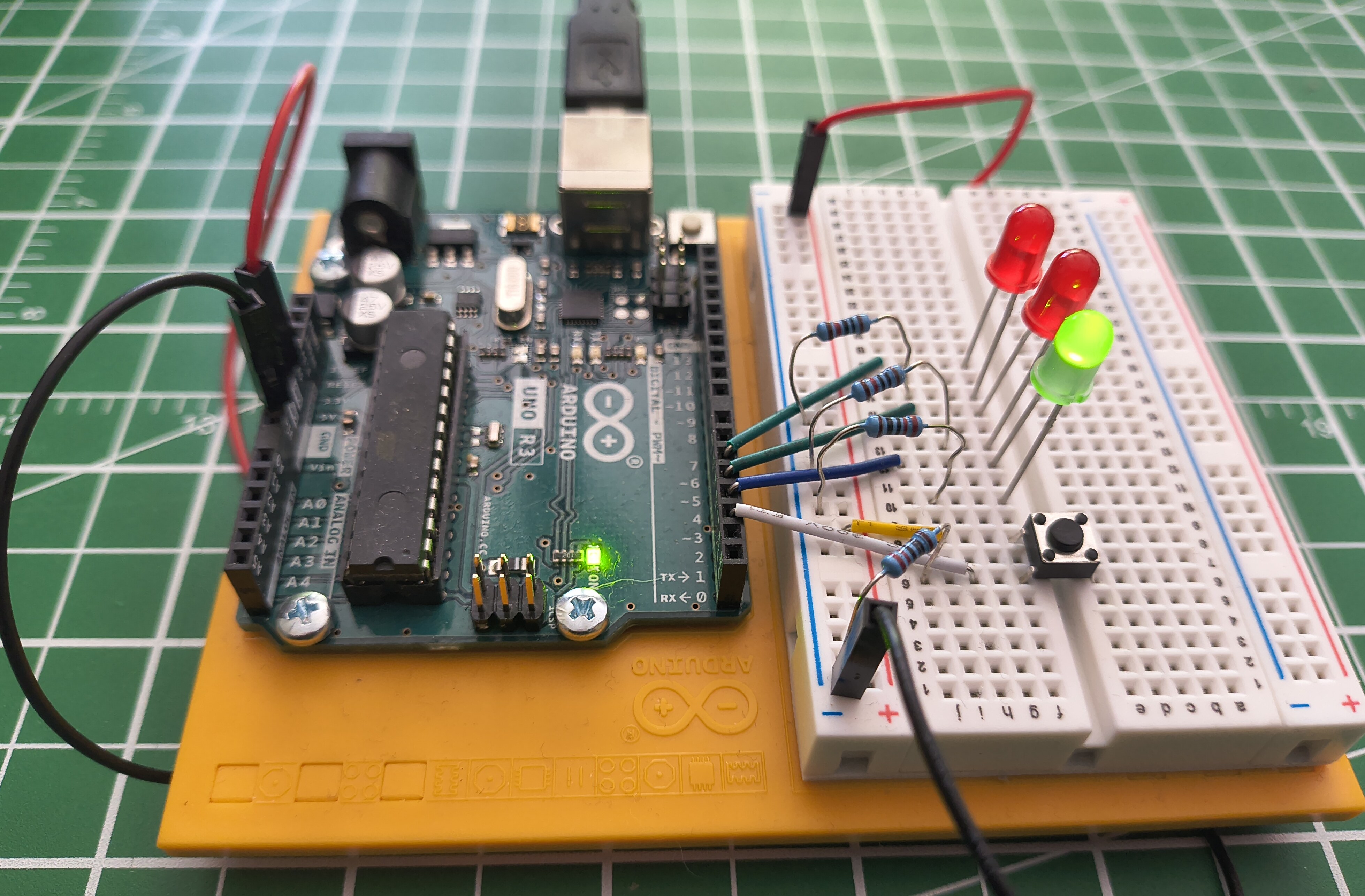 The same Arduino circuit, now powered over USB. The board's ON light glows and the green LED on the breadboard is lit.