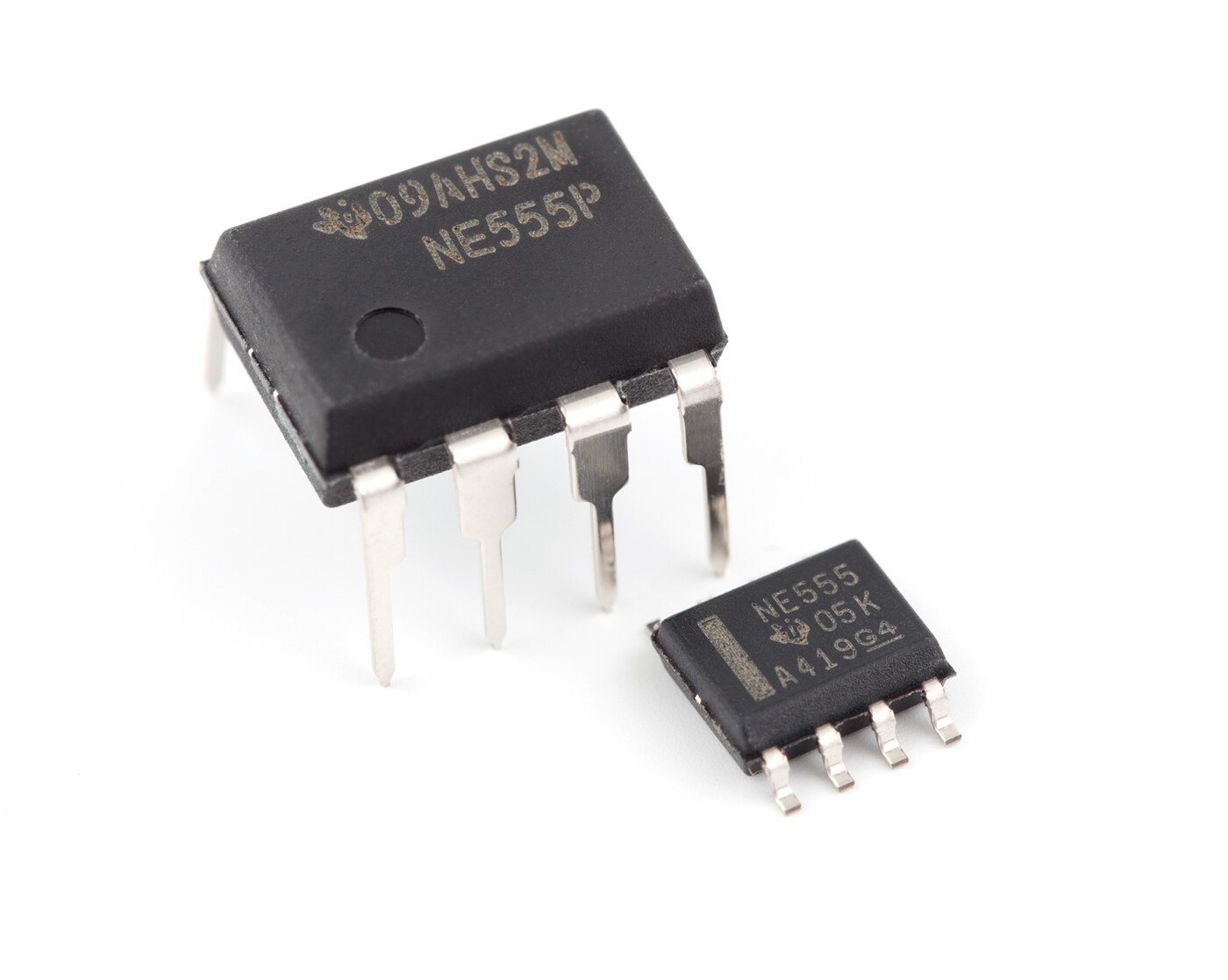 An NE555 timer IC in two packages side by side: a larger 8-pin DIP body with through-hole legs, and a much smaller 8-pin SOIC body with flat surface-mount legs.