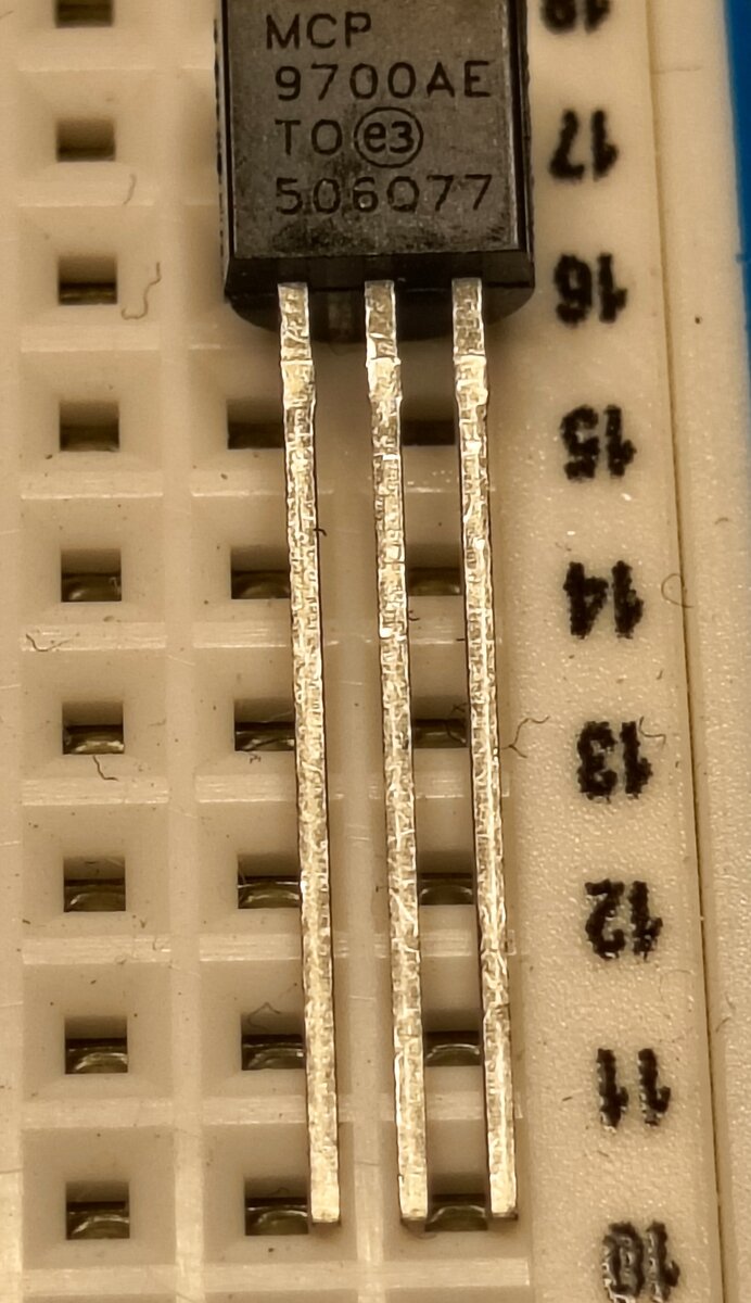 A small black TO-92-packaged MCP9700A temperature sensor plugged into a breadboard, showing its three metal legs.